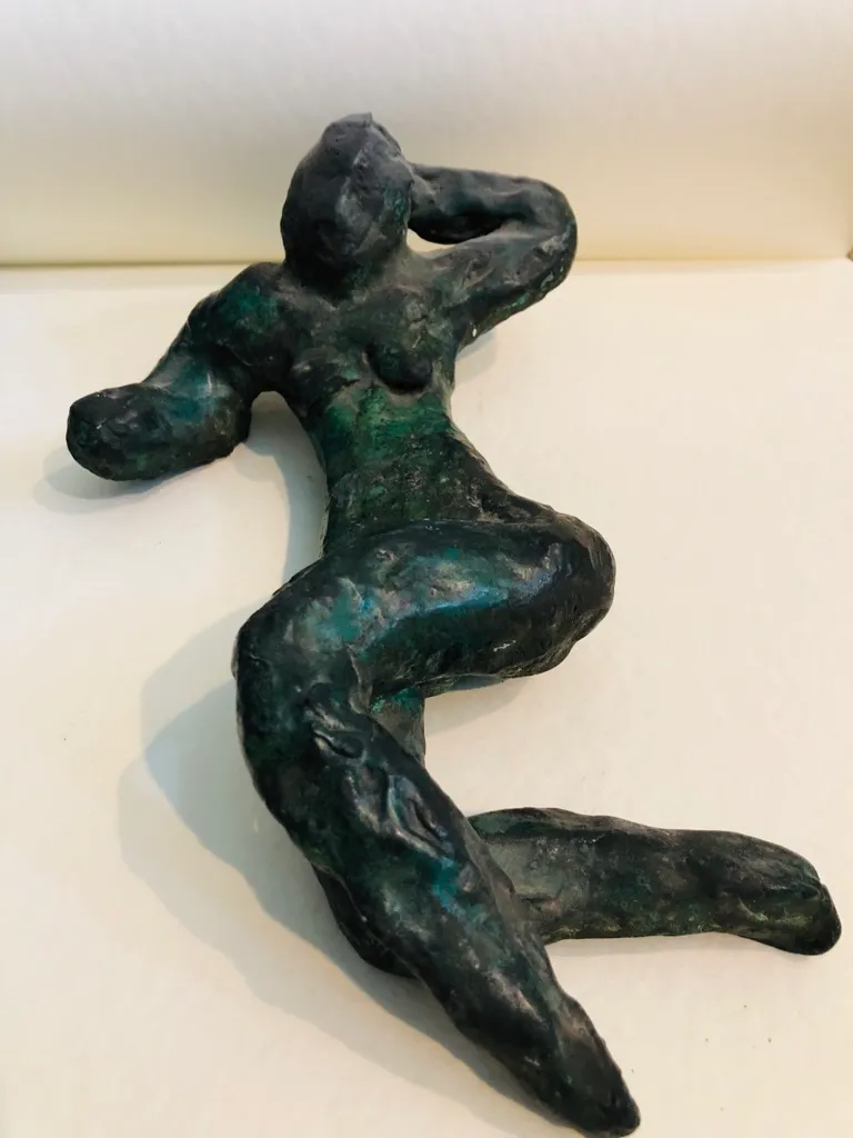 The green-patinated figure from above, her body turning in a long S-curve.