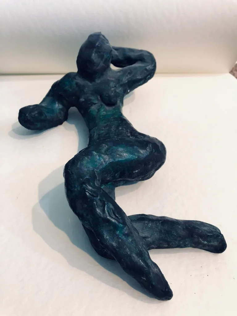 The same green figure lit from the front, the patina turning blue along her legs.