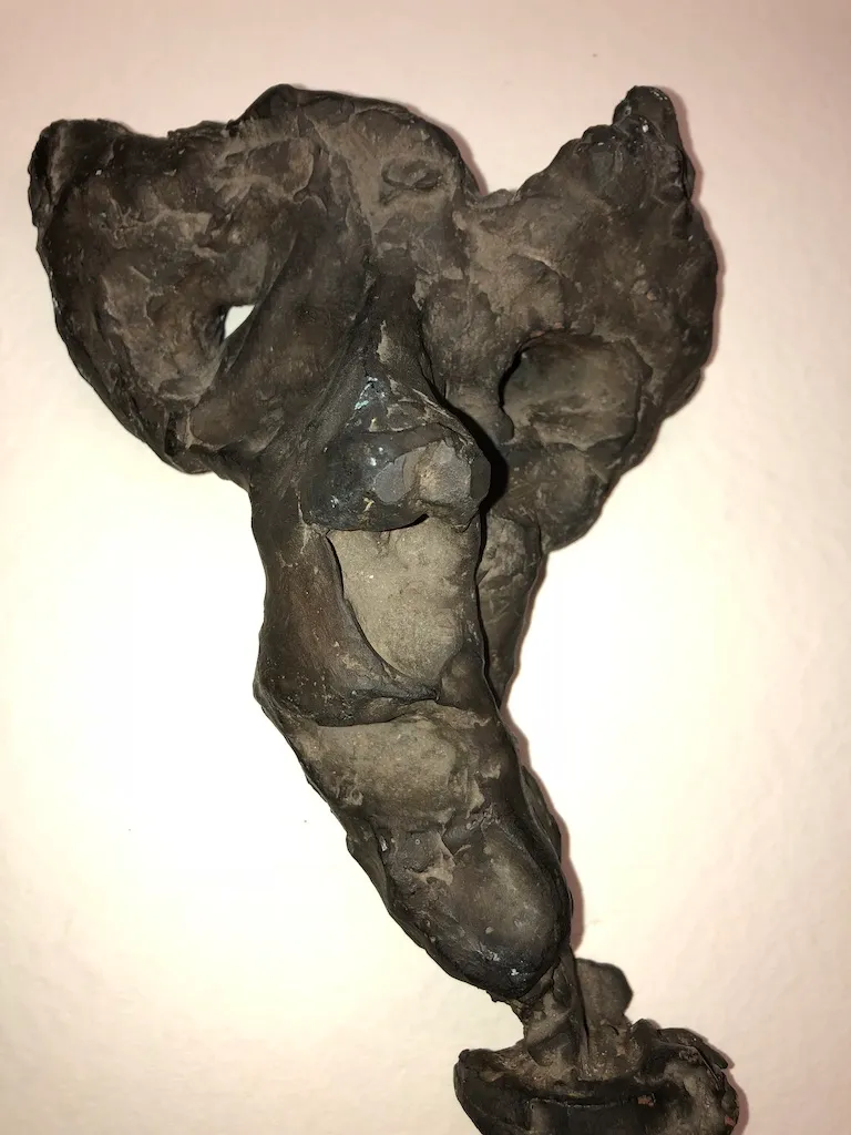 A dark, eroded torso on a wall, hollowed through at the chest and shoulders.