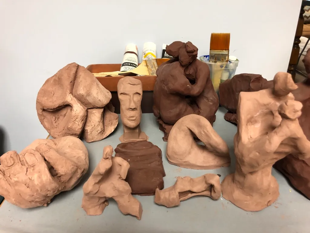 The same studio table from another angle, paint tubes and brushes standing behind the clay figures.
