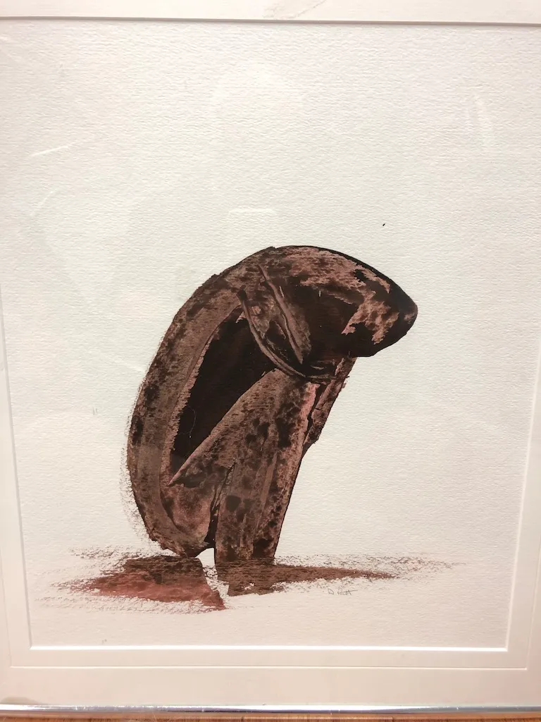 A framed wash painting on paper: a hunched brown figure bowed forward above its own spreading shadow.