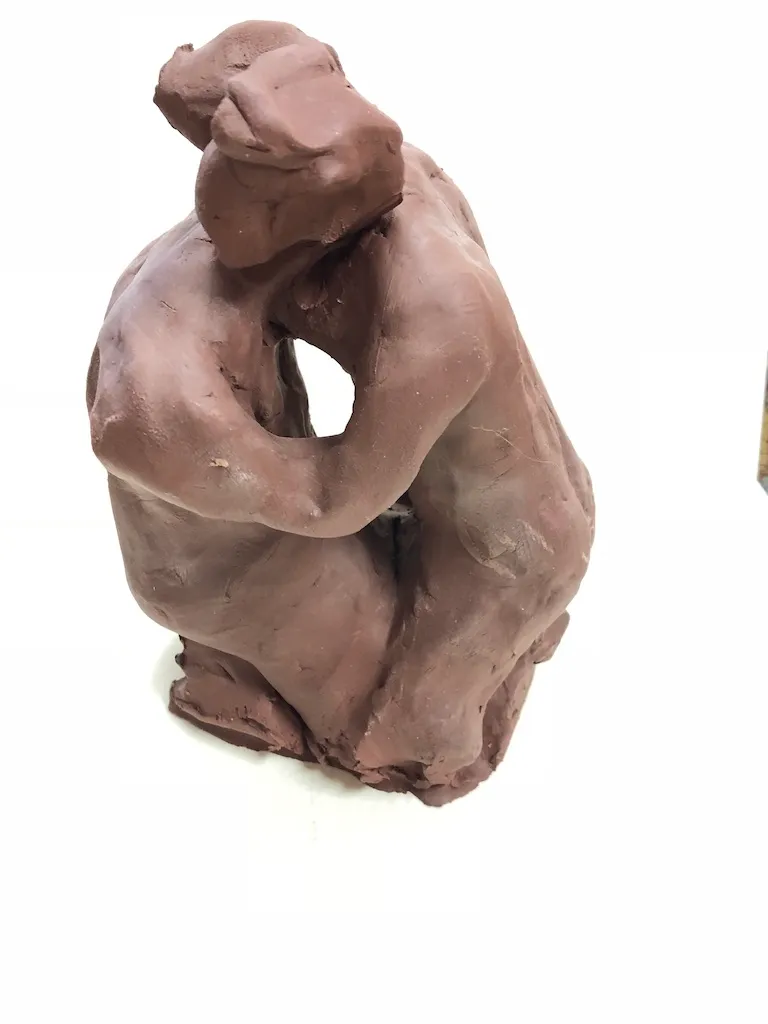The kneeling clay figure, its arms circling an empty space at its centre.